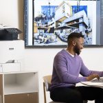 Men working on a laptop in front of a Xerox® VersaLink® C415 Colour Multifunction Printer